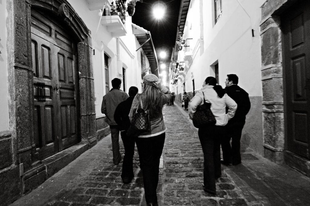 Group of people walking down a charming cobblestone street in Quito at night.